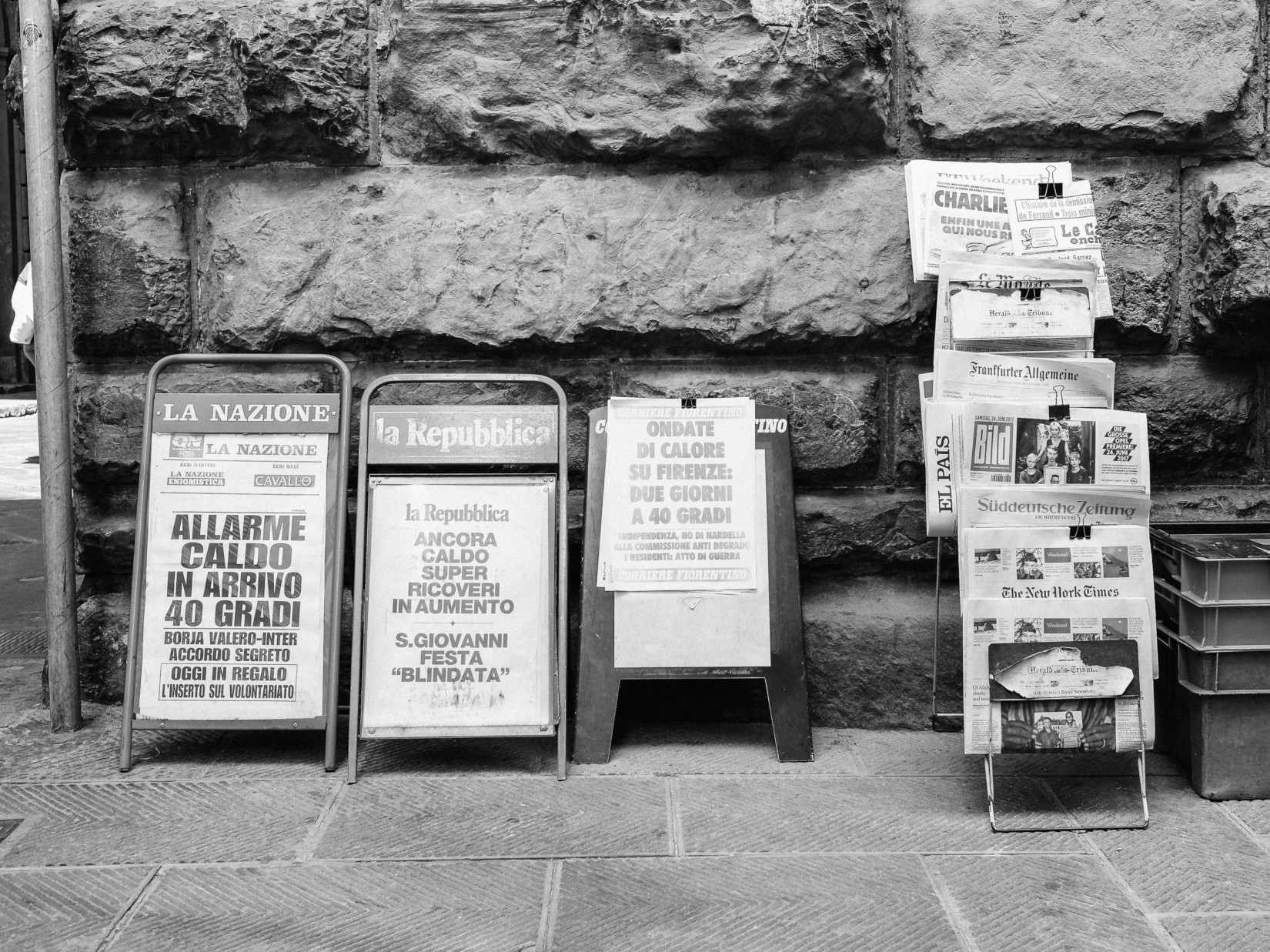 Greyscale image of newspapers on a stand.